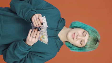 Vertical-video-of-Young-woman-counting-money-looking-at-camera.
